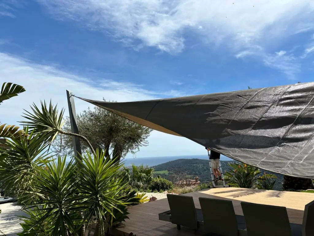 Luxe tuin in Spanje in opbouw, met een zwembad en een relaxhoek in aanbouw, waar een schaduwdoek wordt geïnstalleerd voor toekomstige schaduw en bescherming tegen de zon
